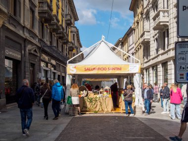 Cremona, Lombardy, İtalya 14 Ekim 2024 Güneşli bir günde beyaz çadırlı bir gıda pazarına yaklaşan insanlar