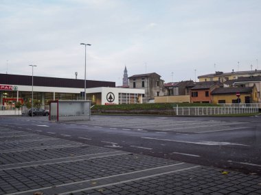 Cremona, Lombardy, İtalya 14 Ekim 2024 Cobblestone park alanı arka planda küçük bir İtalyan köyü manzaralı bir alışveriş merkezine bakıyor.