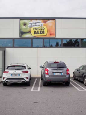 Cremona, Lombardy, İtalya 14 Ekim 2024 Arabalar ön cephesinde her gün düşük fiyatlarla satılan İtalyan reklam panosuyla bir Aldi süpermarketinin önüne park edilir.