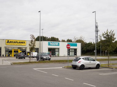 Cremona, Lombardy, İtalya 14 Ekim 2024. Arka planda bulutlu bir gökyüzü olan bir alışveriş merkezinin önüne park edilmiş bir otopark.