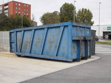 Cremona, Lombardy, İtalya 14 Ekim 2024 Büyük bir mavi metal çöp konteynırı bir otoparkta duruyor, çöplerle doldurulmayı bekliyor