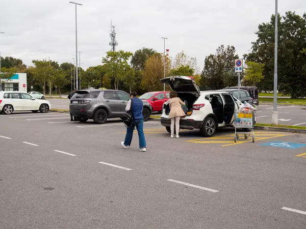 Cremona, Lombardy, İtalya 14 Ekim 2024 Bir çift bulutlu bir günde süpermarketin otoparkına yiyecek yüklüyor.