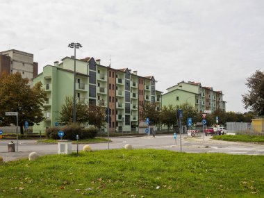 Cremona, Lombardy, İtalya 14 Ekim 2024 Bulutlu bir günde yeşil çimen ve yol işaretleriyle çevrili bir döner kavşak modern apartman binalarıyla çevrili.