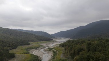 Lago di Mignano, Val Tolla, PC, İtalya - 12 Ekim 2024 Rüzgarlı nehir bulutlu bir gökyüzü altında yemyeşil tepeler boyunca akar ve doğanın sakin bir manzarasını sunar. İago di 