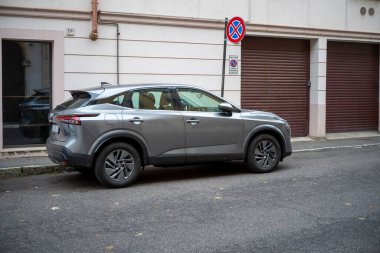 Cremona, Lombardy, İtalya 15 Ekim 2024 Parlak metalik gri bir Nissan SUv büyüleyici bir Avrupa caddesine park etmiş ve şehir manzarasına kentsel gelişmişlik katmış.