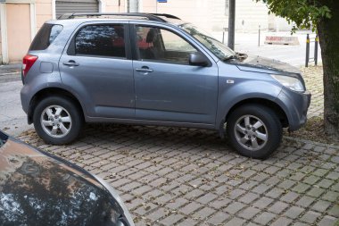 Cremona, Lombardy, İtalya 15 Ekim 2024 gri bir Daihatsu Terios yaya geçidi kaldırımına park edilmiş, yapraklar etrafa saçılmış.