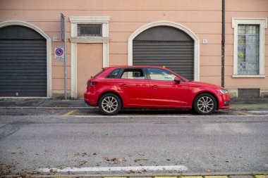 Cremona, Lombardy, İtalya 15 Ekim 2024 Audi A3 kırmızı arabası Avrupa 'da bir iskan caddesinin kenarına park edilmiş, tipik mimari ve sokak manzarası sergilenmektedir.