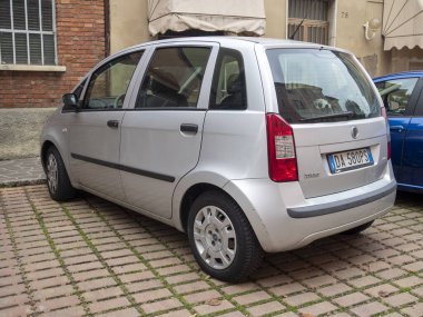 Cremona, Lombardy, İtalya 15 Ekim 2024 Çimen patikasının önüne gümüş bir keman fikri park edilmiş ve şehir manzarasına biraz pratik katılmış.