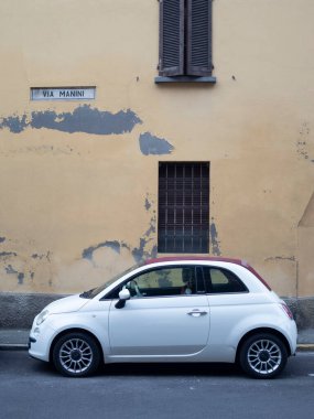 Cremona, Lombardy, İtalya 15 Ekim 2024 Beyaz Fiat 500 İtalya 'da bir caddede kırmızı çatı ve arka planda eski, yıpranmış bina cephesi