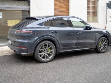Cremona, Lombardy, İtalya 15 Ekim 2024 Modern elektrikli SUV Porsche cayenne coupe ve hibrit bir Avrupa şehir caddesi üzerine park edilmiş, parlak tasarımı ve çevre dostu teknolojisi sergilenmektedir.