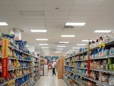 Cremona, Lombardy, İtalya. 27 Ekim 2024. Kadın, çeşitli ürünler ve düşük fiyatlı tabelalarla dolu bir süpermarkette alışveriş yapıyor.