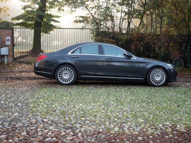 Cremona, Lombardy, İtalya 27 Ekim 2024 Lüks siyah Mercedes Benz sınıfı huzurlu bir yerleşim alanındaki kaldırım taşlı bir yola park etmiş.