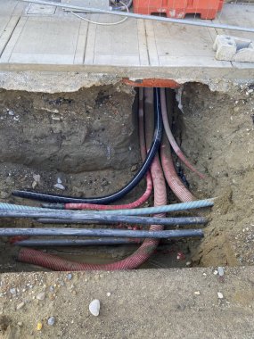 Piacenza, İtalya 15 Ekim 2024 Renkli elektrik kabloları ve kanalları, altyapı veya kamu hizmetleri çalışmaları sırasında yerin altına kazılan bir siperde görülebilir.