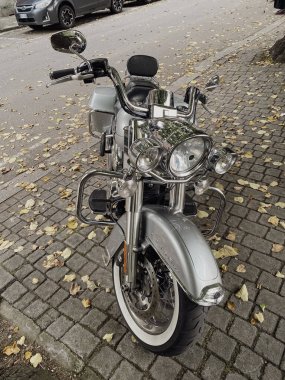 Piacenza, İtalya 15 Ekim 2024 Parlayan Krom ve Gümüş Harley Davidson elektra süzülüşü kaldırım taşı sokağına park edilmiş, düşen sonbahar yapraklarıyla süslenmiş, özgürlük ve maceranın simgesi.