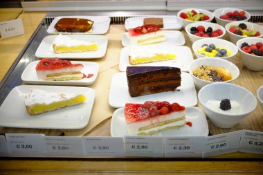 Traversetolo, Parma, genellikle - 6 Kasım 2024 Pasta dilimleri ve taze meyve malzemeleriyle baştan çıkarıcı tatlılar bir pastanenin vitrininde sergileniyor, müşterileri tatlı teklifleriyle cezbediyor.