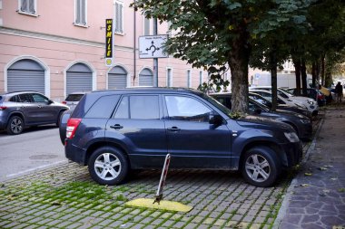 Cremona, Lombardy, Italy - November 7th 2024 Dark blue suv taking up two parking spots with a yellow lock and pole on the ground preventing it from leaving clipart