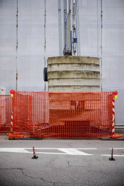Cremona, Lombardy, İtalya - 7 Kasım 2024 İnşaat alanında turuncu plastik güvenlik ağı arkasında yığılmış beton bloklar