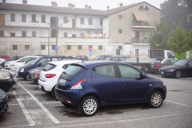 Cremona, Lombardy, İtalya - 7 Kasım 2024 Sisli bir günde otoparkın önüne park edilmiş arabalar