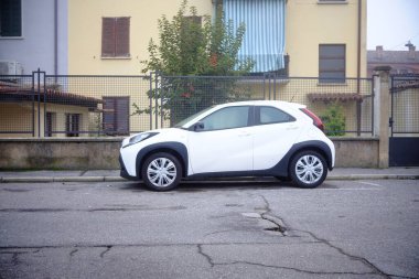 Cremona, Lombardy, İtalya - 7 Kasım 2024 Modern kompakt toyota aygo arabası bir konut binasının yakınındaki kırık asfalt yolda park edilmiş, kentsel park sorunları sergileniyor