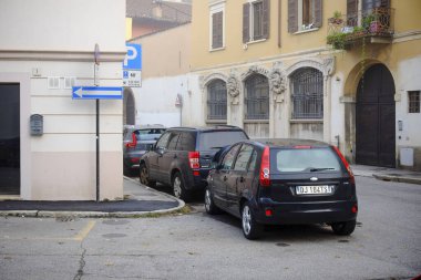 Cremona, Lombardy, İtalya - 7 Kasım 2024 Eski bir italyan kasabasında dar bir cadde boyunca park alanlarını işgal eden araçlar,