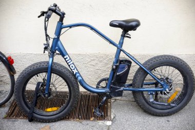 Cremona, Lombardy, İtalya - 7 Kasım 2024 Bej bir duvarın yanına park edilmiş elektrikli motosiklet sürdürülebilir şehir ulaşımını gösteriyor