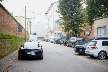 Cremona, Lombardy, İtalya - 7 Kasım 2024 Black Porsche 718 cayman dar bir iskan caddesine park edilmiş ve arka planda devam eden inşaat görünür.