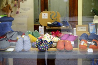 Cremona, Lombardy, Italy - November 7th 2024 Various slippers are neatly arranged in a store window display, showcasing different colors, patterns, and materials for sale clipart