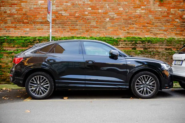 Cremona, Lombardy, İtalya - 7 Kasım 2024 Modern siyah audi q3 spor arazi aracı yosunlu tuğla duvarın yanına park edilmiş,