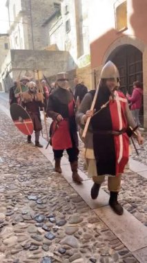 Castell 'Arquato, İtalya - 15 Eylül 2024 Ortaçağ kostümlü bir grup Rivivi il Medioevo' nun tarihi yeniden canlandırma festivali sırasında kaldırım kenarında yürüyor