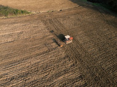 Martani 'de, Castell' Arquato, PC, Italy Farmer traktör ve harrow ile tarla sürme alanı, tarımda toprak hazırlığının havadan görünüşü. Martani 'de, Castell' Arquato, PC, İtalya