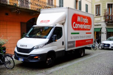 Cremona, genel olarak - 6 Ekim 2024 Beyaz Iiveco günlük kamyonu şehir ortamında bir kaldırım taşı sokakta mondo uygun bir reklam sergiliyor.