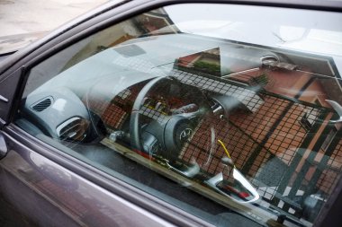 Cremona, Itally - October 6th 2024 Building reflecting in the window of a parked gray toyota aygo x 1.0 vvt-i, model year 2022 clipart