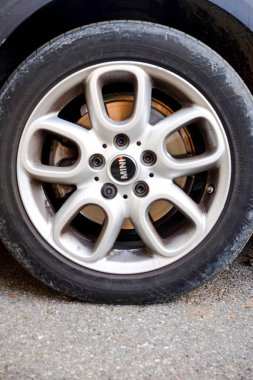 Cremona, normalde 6 Ekim 2024 'te asfalta park etmiş küçük bir fıçı r56 üzerinde kirli gümüş alaşımlı tekerlek ve lastiğin yakın çekimi. Karmaşık detaylar ve zıt renkler gösteriliyor