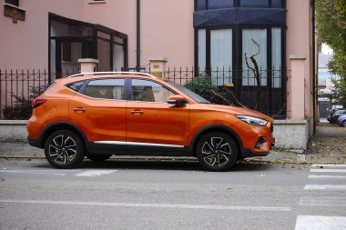 Cremona, Ially - 6 Ekim 2024 şık ve canlı: modern turuncu bir mg zs ev bir yerleşim caddesinde, şık tasarımı ve kalın rengi sergilenmektedir