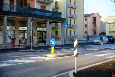 Cremona, İtalya - 7 Kasım 2024 Trafik levhasında belirtilen, kavşağa yaklaşan araçların akışını düzenleyen, arka planda eczane bulunan bir trafik işareti