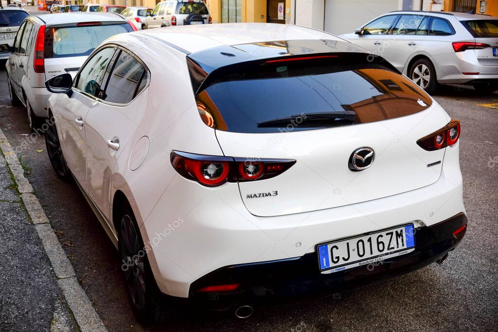 Cremona, Itally - October 6th 2024 White mazda 3 hatchback 2.0 skyactiv-x parked on a city street, highlighting its modern design and sleek features from the rear view