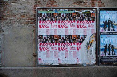 Cremona, İtalya - 15 Kasım 2024 Orfeo haftası ve yıpranmış tuğla bir duvarda sergilenen müzikal mamma Mia da dahil olmak üzere kültürel etkinlikleri destekleyen reklam afişleri