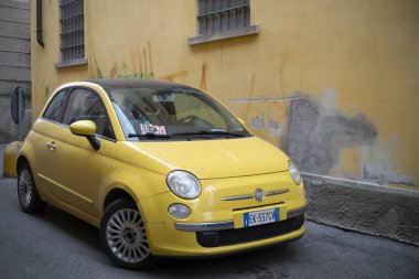 Cremona, İtalya - 15 Kasım 2024 Parlak sarı fiat 500 Grafiti kaplı bir duvar yanına park edilmiş tipik bir İtalyan şehir manzarası