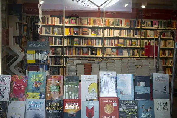 Cremona, İtalya - 20 Kasım 2024 Renkli kitap kapakları bir kitapçı vitrininde sergilenirken, çeşitli türlerde müşterileri baştan çıkarırken, tam kitap rafları içinde geniş bir seçim sunuyor