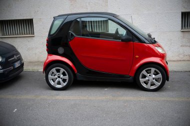 Cremona, Lombardy, İtalya - 27 Ekim 2024 Bir kırmızı ve siyah akıllı iki coupe için bir cadde kenarında park edilmiş, küçük boyutu ve iki tonluk tasarımı sergilenmektedir
