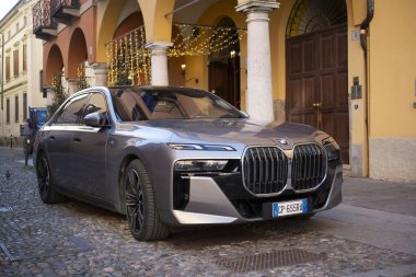 Cremona, Lombardy, İtalya - 27 Ekim 2024 Zarif bmw i7 xdrive 60 elektrikli sedan tarihi bir binanın yakınına park edilmiş sürdürülebilir lüks ve otomotiv tasarımı sergilenmektedir.
