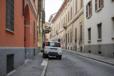 Cremona, Lombardy, İtalya - 27 Ekim 2024 Beyaz Fiat sedici eski bir İtalyan kasabasında dar bir sokağa park edilmiş, Avrupa kentsel yaşamını gözler önüne seriyor
