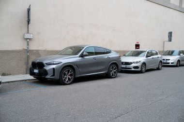 Cremona, Lombardy, İtalya - 27 Ekim 2024 BMW x6 m yarışma, gökdelen metalik gri, v8 motor, 2021, Fiat tipo ve Suzuki Swift 'in yanında
