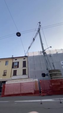 Cremona, İtalya - 9 Aralık 2024 İnşaat alanı hareketli, parlak, güneşli bir sonbahar gökyüzü altında bir vinç ve kamyonun yer aldığı