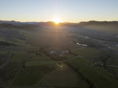 Sıcak güneş ışığı, günbatımında manzara yaratan Castell 'Arquato, Arda Vadisi, Piacenza, İtalya' daki ekili tarlaları ve çiftlik evlerini aydınlatır.