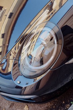 Cremona, İtalya - 15 Ocak 2025 Cilalanmış koyu mavi Porsche 911 Parlak, güneşli bir günde bir binanın ön cephesinin parlak hatlarını yansıtıyor
