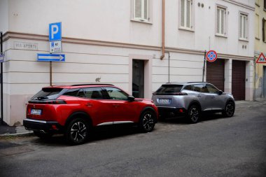 Cremona, Italy - December 24th 2024 Red Peugeot 2008 and silver DS 3 Crossback parked in an urban setting, showcasing modern automotive design and city life clipart