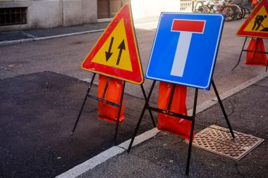 Cremona, İtalya - 30 Ocak 2025 Bir şehir caddesinde iki geçici trafik levhası duruyor, sürücüleri yaklaşan yol çalışması ve kapalı şerit konusunda uyarıyorlar. Turuncu emniyet çantaları tabanda görünür.