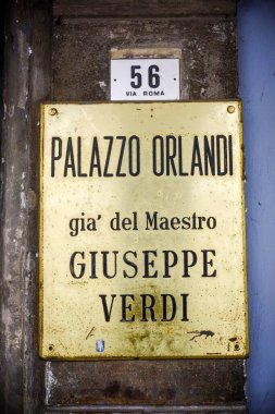 Busseto, Parma, İtalya - 31 Ocak 2025 Via Roma 'da bir binaya konulan yıpranmış pirinç plaket, Palazzo Orlandi' yi ünlü besteci Giuseppe Verdi 'nin eski evi olarak tanımladı. Bina numarası.