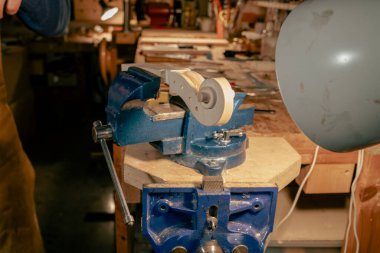 Luthier yeni bir keman parşömeni üzerinde çalışıyor. Lambayla aydınlatılan bir atölyede dikkatlice emniyete alıyor. Geleneksel marangozluk ve ahşap işçiliği gösteriyor.